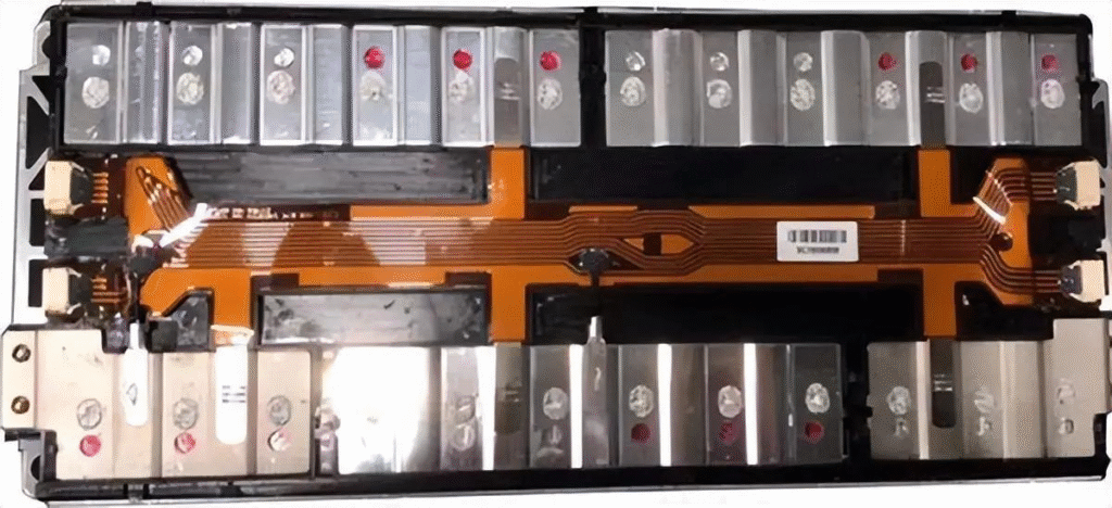 Teardown image of [product/model name] electronic module. Displays orange FPC interconnecting metallic cell - like components, critical for understanding internal design, component sourcing, and assembly process optimization.
